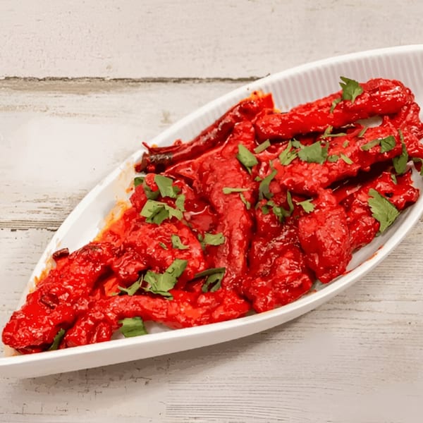 Deccan Flavors' bright red Indian chicken dish, garnished with fresh green cilantro, in a white serving dish.
