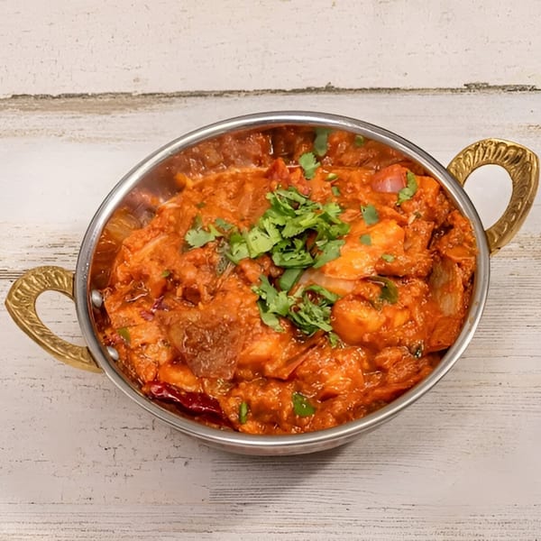 Deccan Flavors' Indian curry, a vibrant orange dish with cilantro garnish, served in a metal bowl.