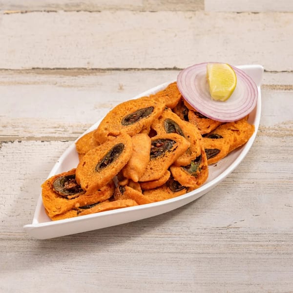 Deccan Flavors' Indian snack, a white boat-shaped dish filled with fried, spiced rolls, garnished with onion and lemon.